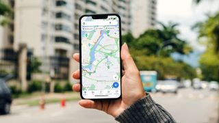 Google Maps shown on an iPhone being held up in the middle of the street