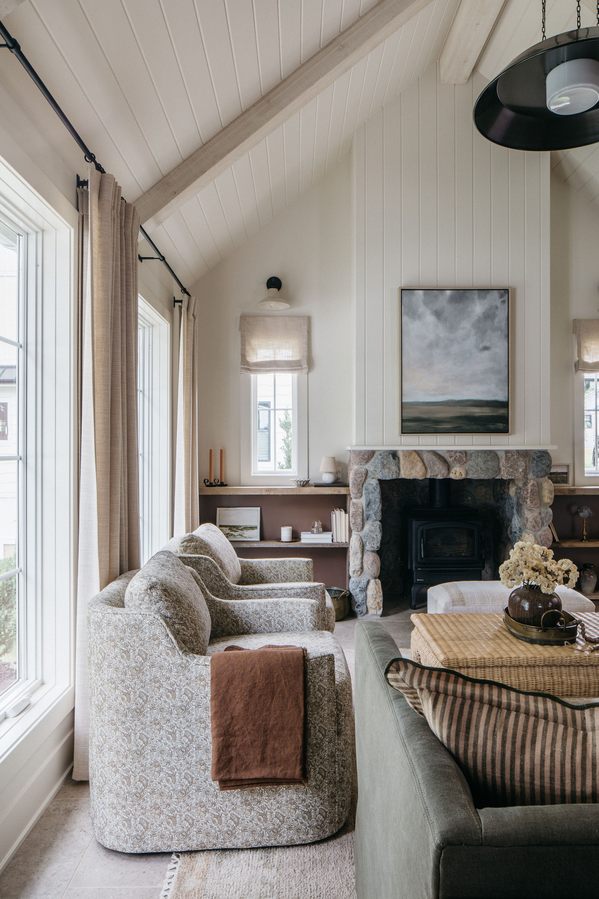 A contemporary living room with high ceilings, featuring textural furniture and a variety of materials