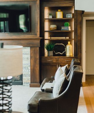 A living room with a dark wooden built-in bookshelf and two leather armchairs