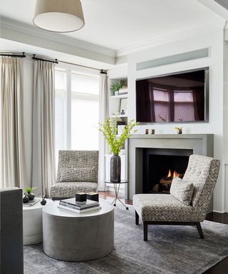 Gray living room with two lounge chairs facing away from tv and fireplace.