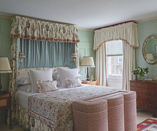 bedroom with fabric canopy and scalloped storage bench at end of bed and patterned bespread