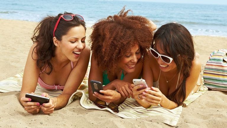 young women on beach with cell phones