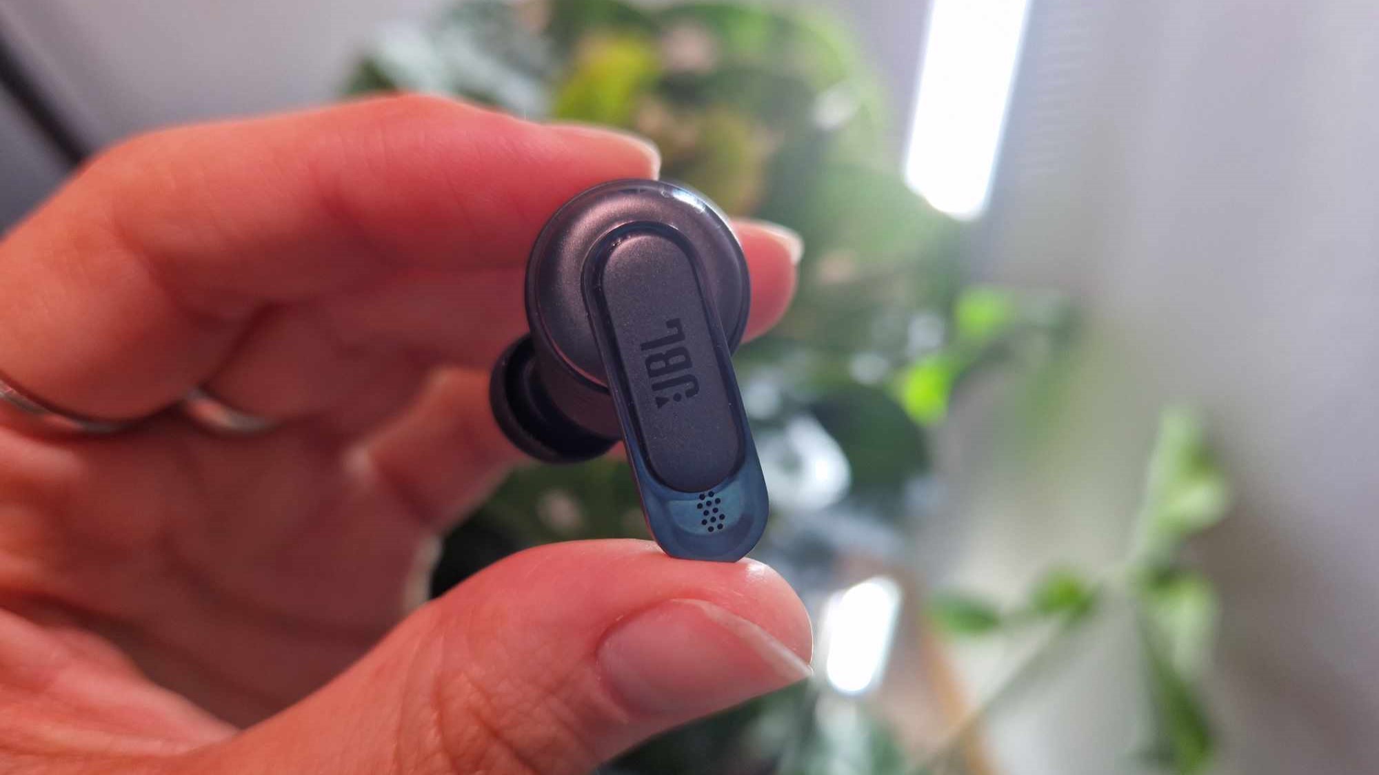 En hand håller upp ena öronproppen till JBL Tour Pro 2.