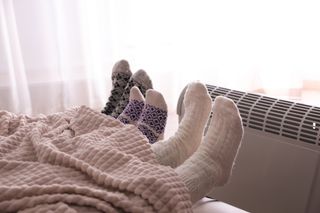 A family warming their feet near an electric heater in their home.