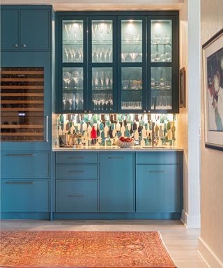 kitchen area with teal cabinets, orange rug and glass-fronted built-in shelving