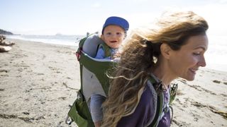 a woman and her young baby hiking along a deserted beach