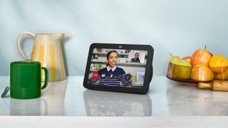 The Amazon Echo Show 8 on a marble counter between a fruit bowl and a coffee mug.