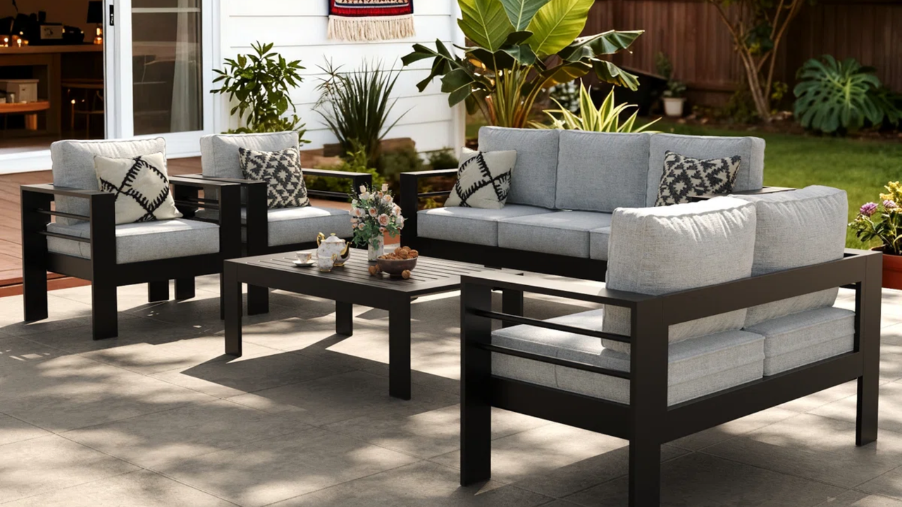 outdoor couches and accent chairs with gray cushions and pillows and a black patio coffee table 