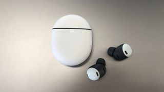 Google Pixel Buds Pro ligger på ett ljusgrått bord.