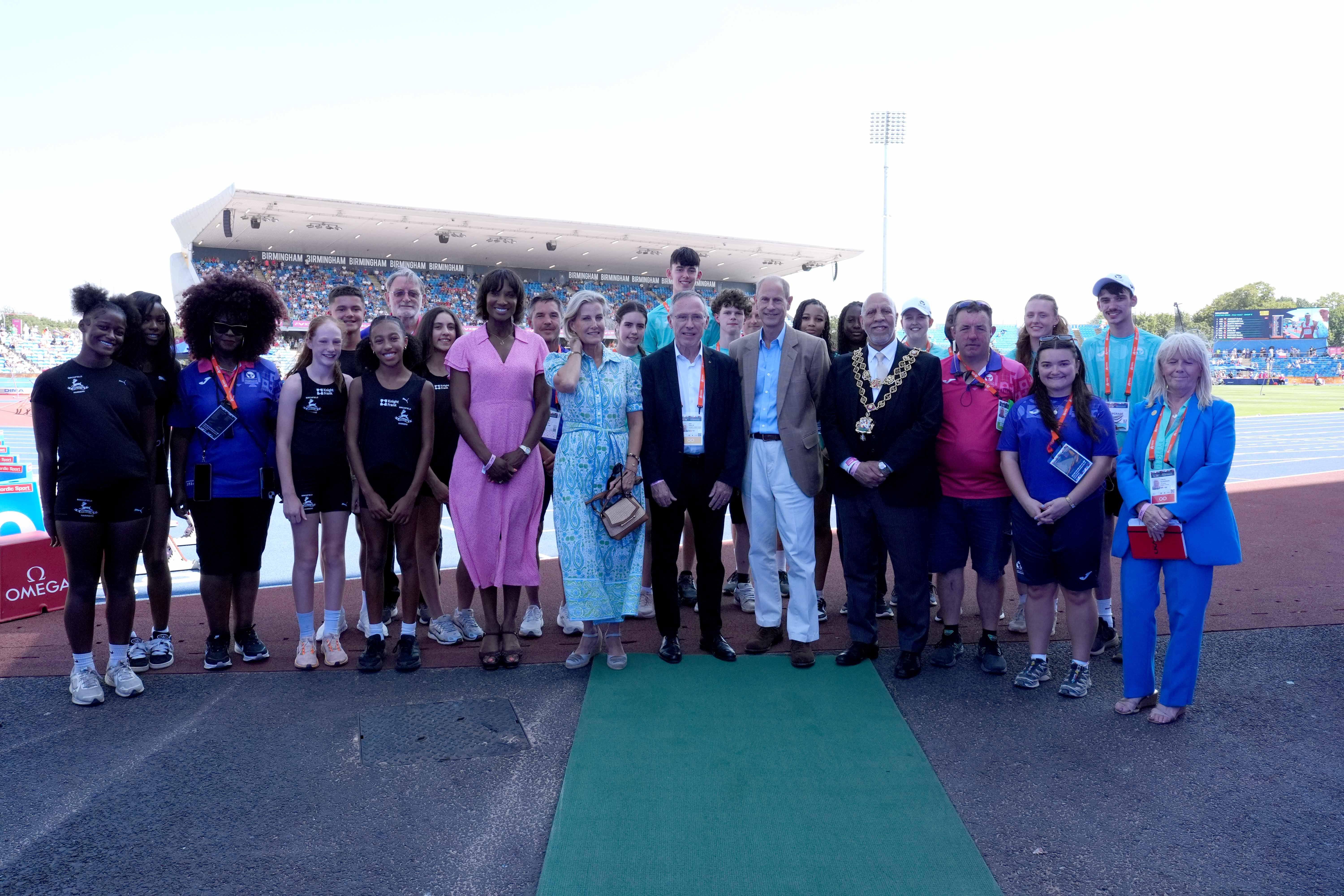 Duchess Sophie wearing a paisley dress standing on a field with athletes