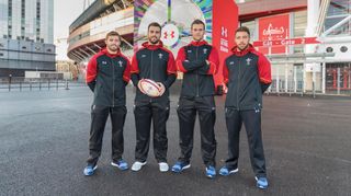 Members of the Welsh Rugby team standing outside a stadium wearing Under Armour tracksuits