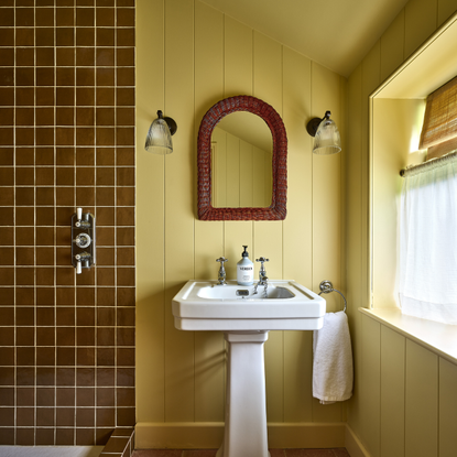 a yellow painted bathroom with brown wall tiles