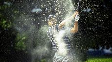 Tiger Woods blasts out of a bunker