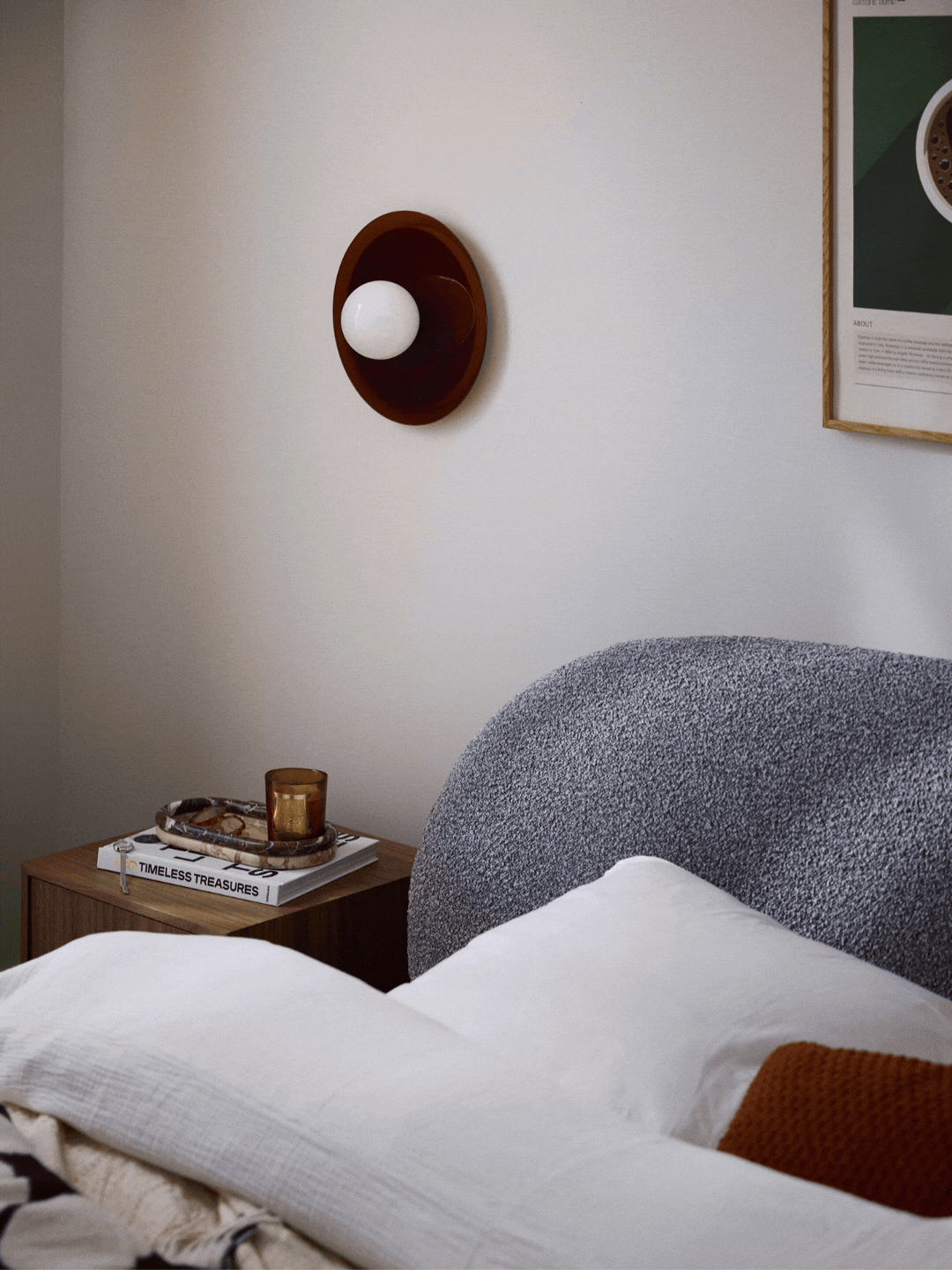 A wall sconce with an exposed bulb and a reflective brown base