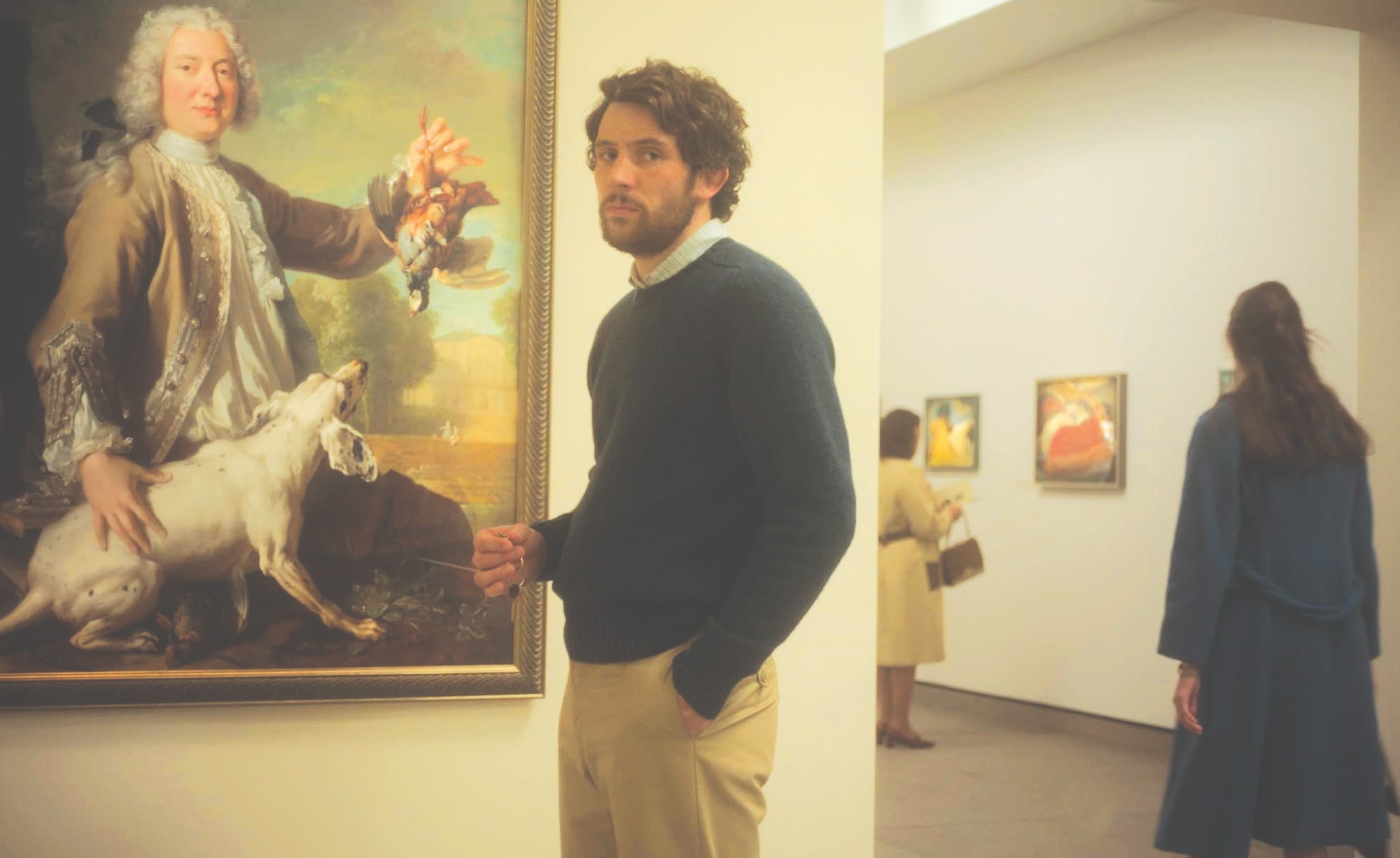 Josh O'Connor poses in front of a painting