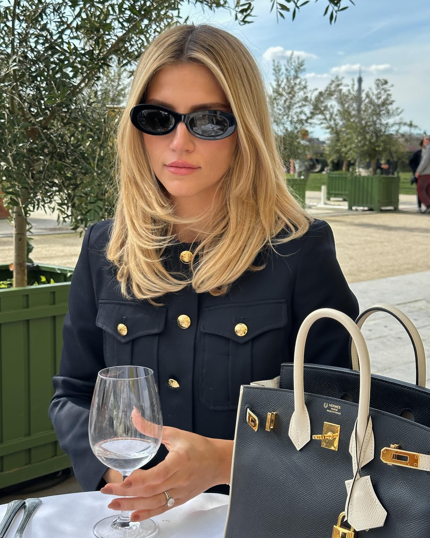 A woman sitting in a cafe in Paris with a bouncy blow-dry