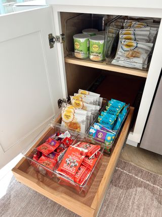 An open kitchen cabinet with a pull-out drawer fitted with organziers