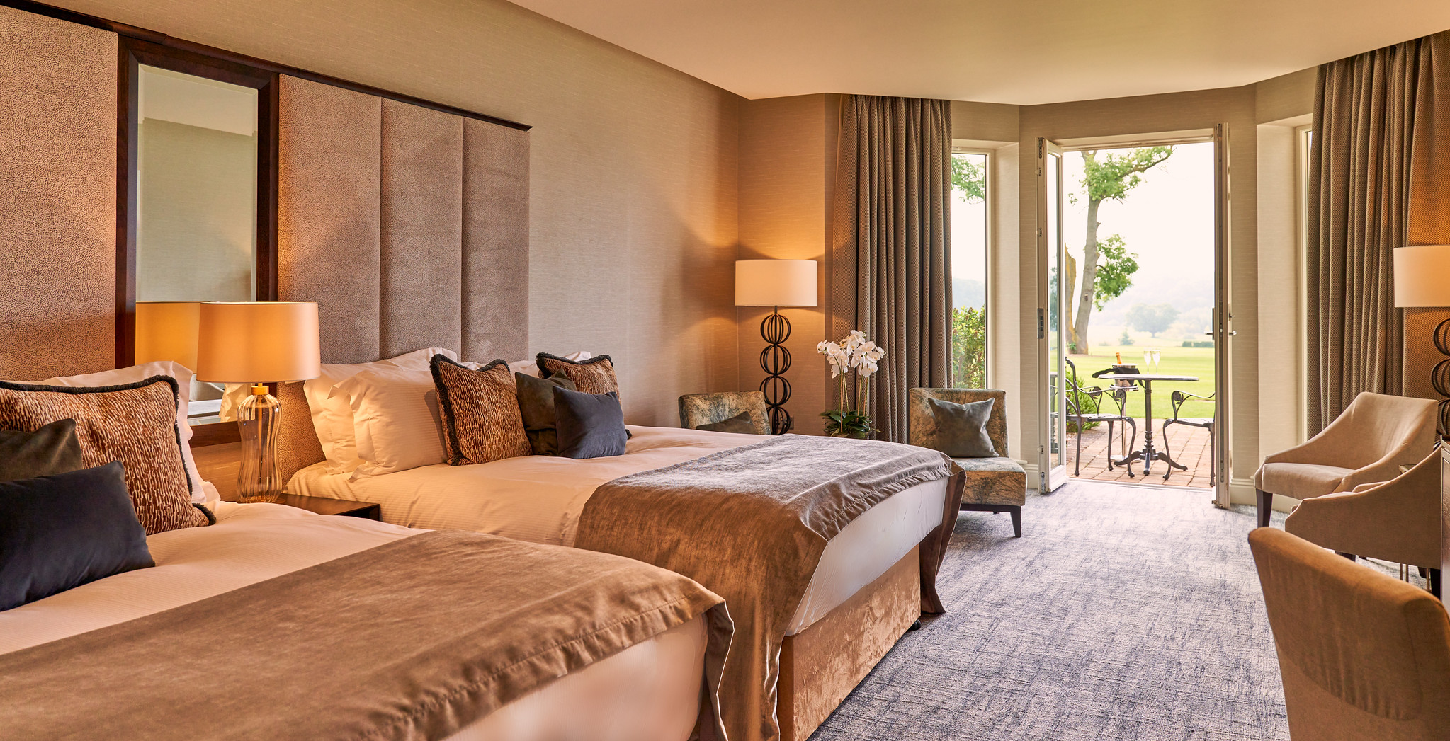 A hotel room with two beds and the doors open to a patio