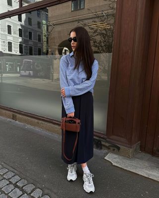 @annabelrosendahl wearing white trainers with a navy skirt