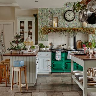 farmhouse kitchen with wallpapered wall behind aga and christmas decorations