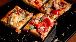 Pizza cut into squares and separated on a baking sheet