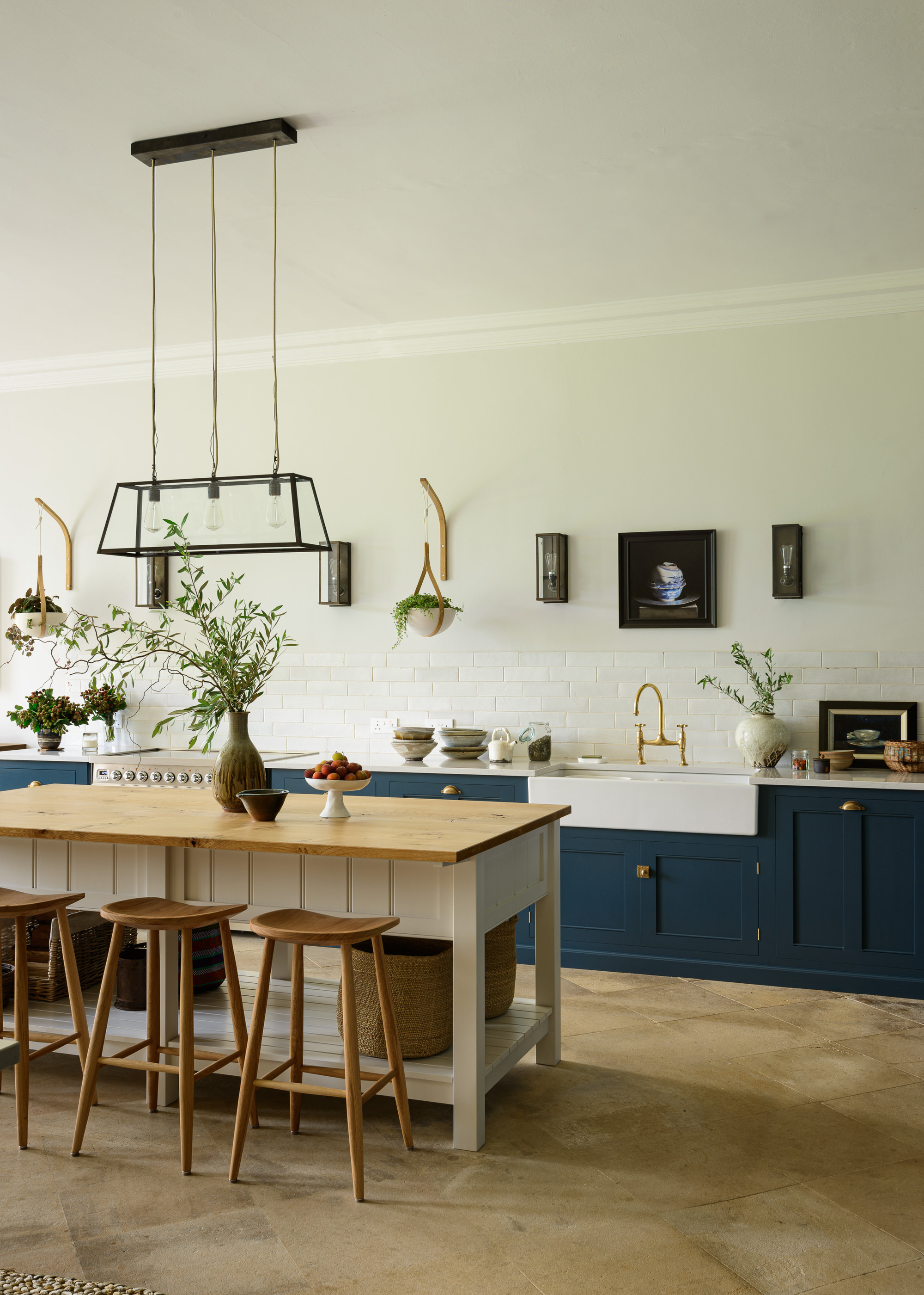 A kitchen with a navy cabinets, a Belfast sink, and a Farmhouse style prep table with wooden stools