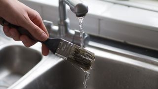 washing a paint brush under a sink