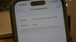 iPhone 14 Pro displays the Text Replacement in iOS to replace "mwa" with a full work address