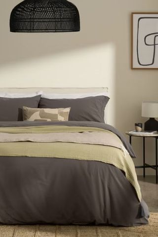 made.com grey bedding on bed with green throw and black bedside table 