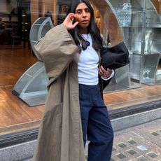 Woman in a trench, white top and navy pants