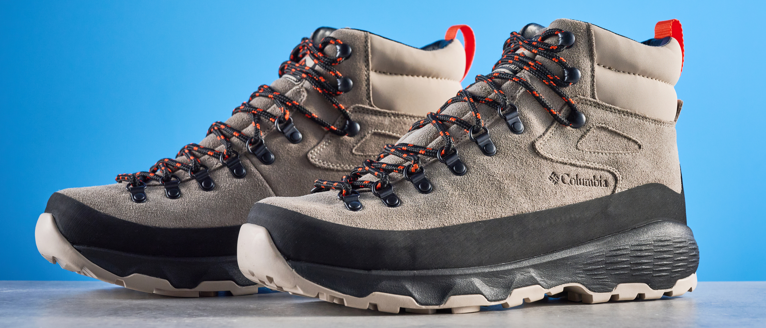 The Columbia Newton Alpine boots on a stone surface with a blue background