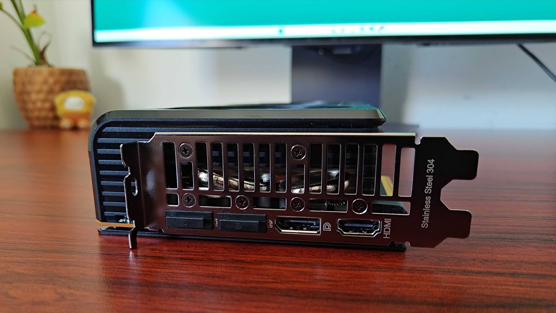 AMD Radeon RX 9070 sitting on woodgrain desk with HDMI and Displayports facing forward.