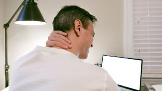 How to get a better posture when working from home: A man experiences neck pain while working from home
