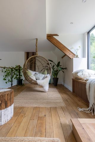 A hanging chair in a loft living room corner with indoor tree houseplant