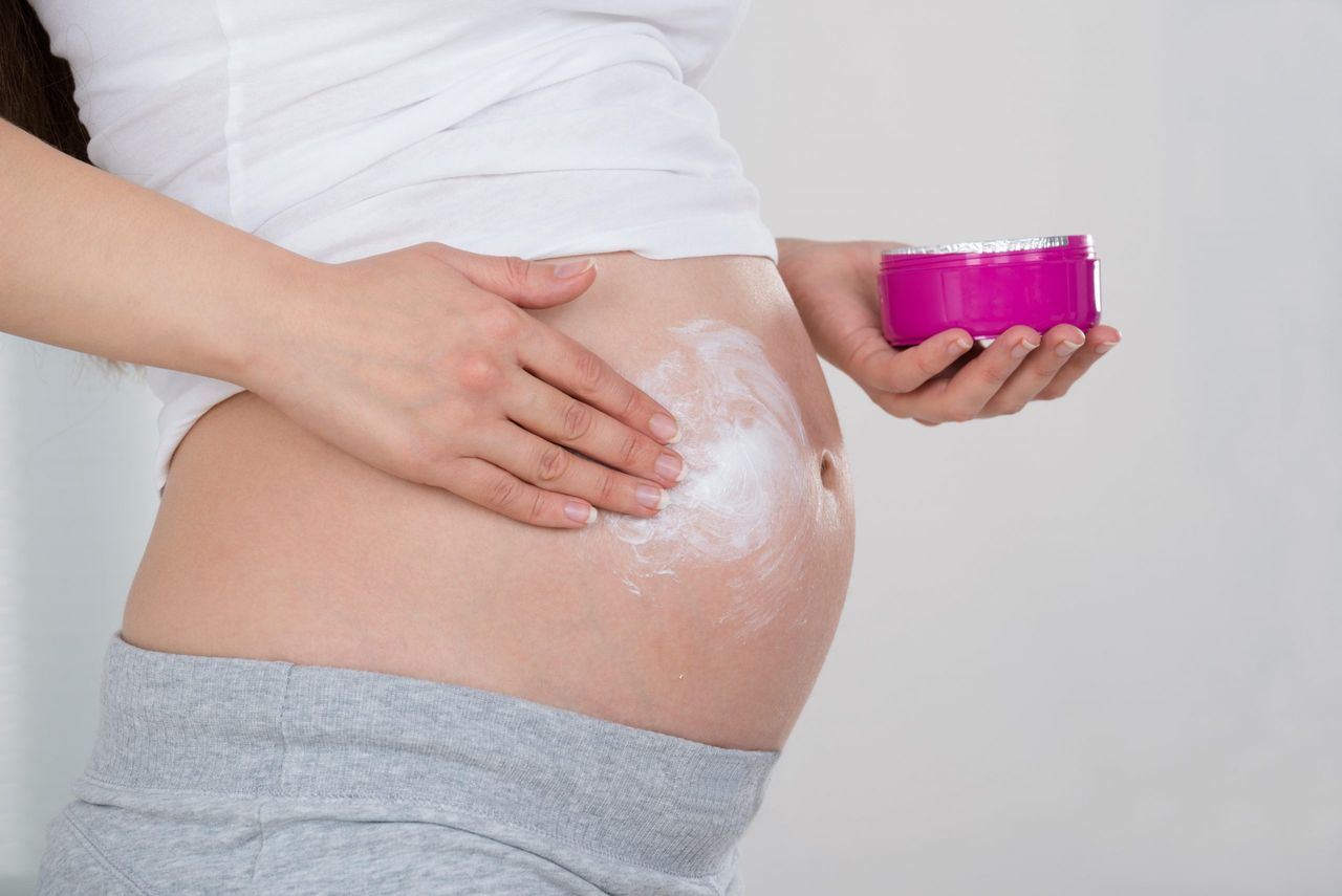 Pregnant Woman Applying Cream On Her Belly