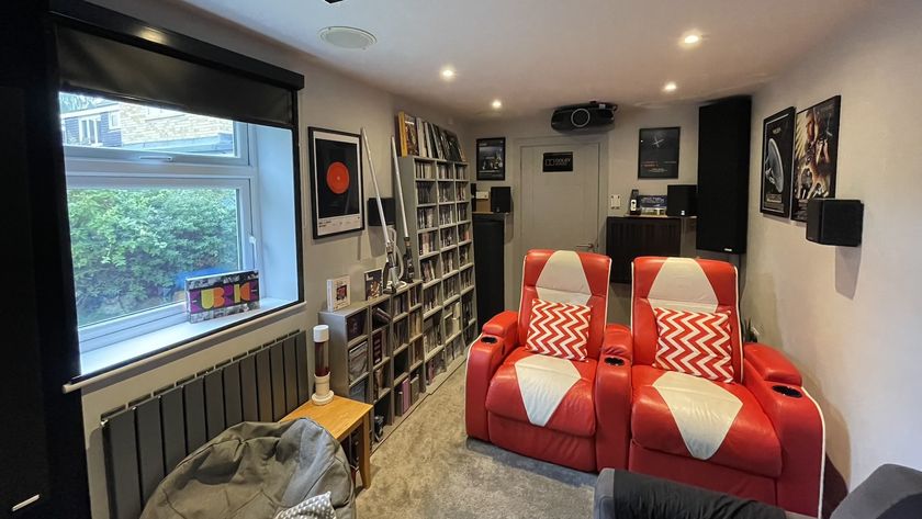 A photograph of a dedicated home cinema room featuring bright red seating