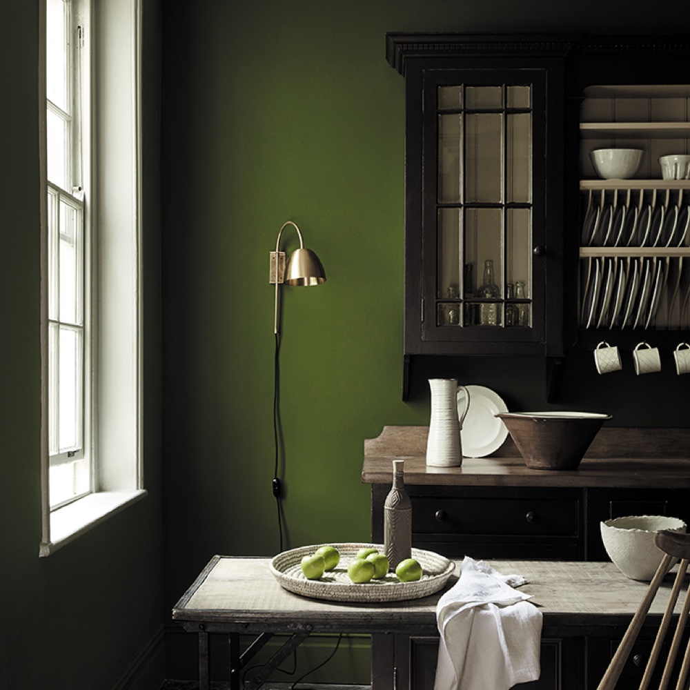 kitchen area with green wall and black kitchen cabinet and table