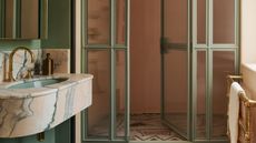 an art deco bathroom with a mosaic decorative floor, and an arched shower screen with pink and green color palette