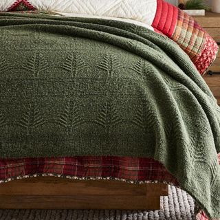 The corner of the Arden Tree Blanket on a bed. 