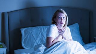 A woman sitting up in bed at night