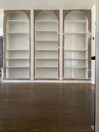 A wall of empty white ikea billy bookcases in the process of renovating with MDF arches