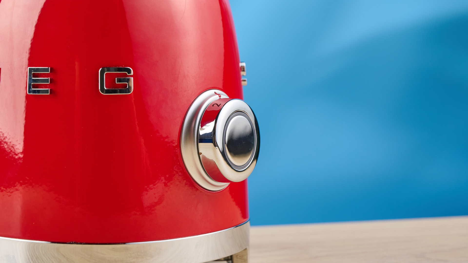 Smeg Personal Blender in the red colorways photographed in front of a blue background.