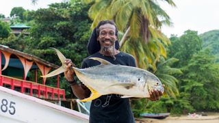 A man holds a fresh fish he caught in Tobago
