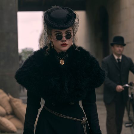 Florence Pugh as Cathy Ames waring a black gown sunglasses and hat as she walks down a street and a man with a bicycle follows her in netflix's east of eden