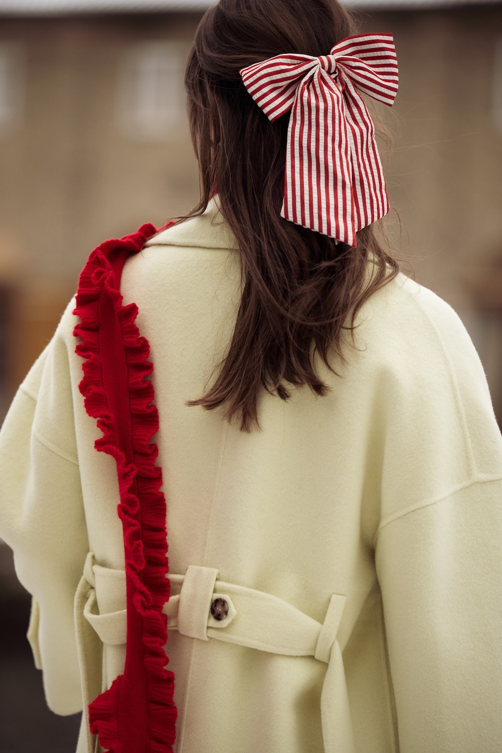 a guest at copenhagen fashion week wearing a hair bow and knit bag