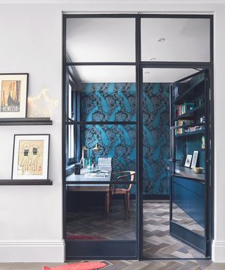 A small office with glass doors, painted dark blue with a feature wall, and parquet floor.