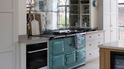 White kitchen with blue Aga and mirrored backplash