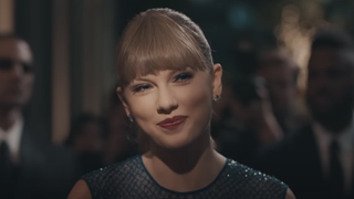 Taylor Swift politely smiles as she talks to paparazzi in the Delicate music video.