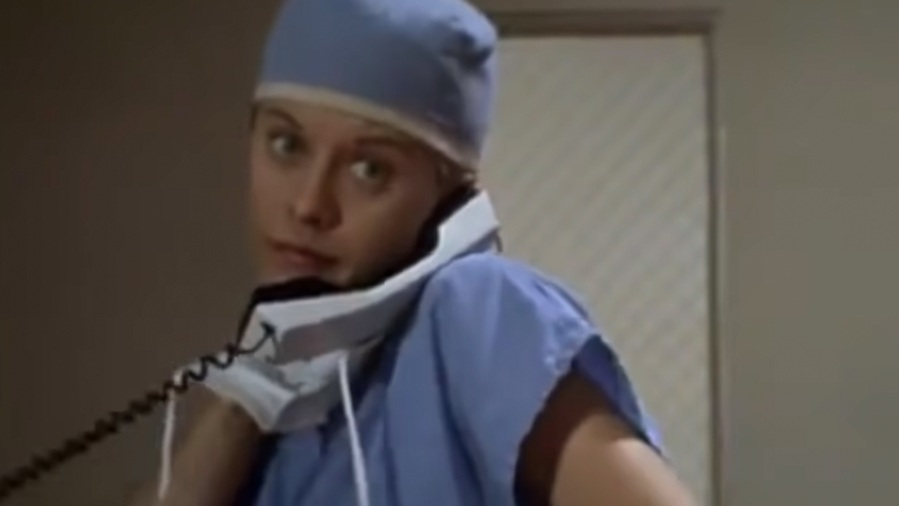 Meg Ryan on a phone, dressed in surgical scrubs