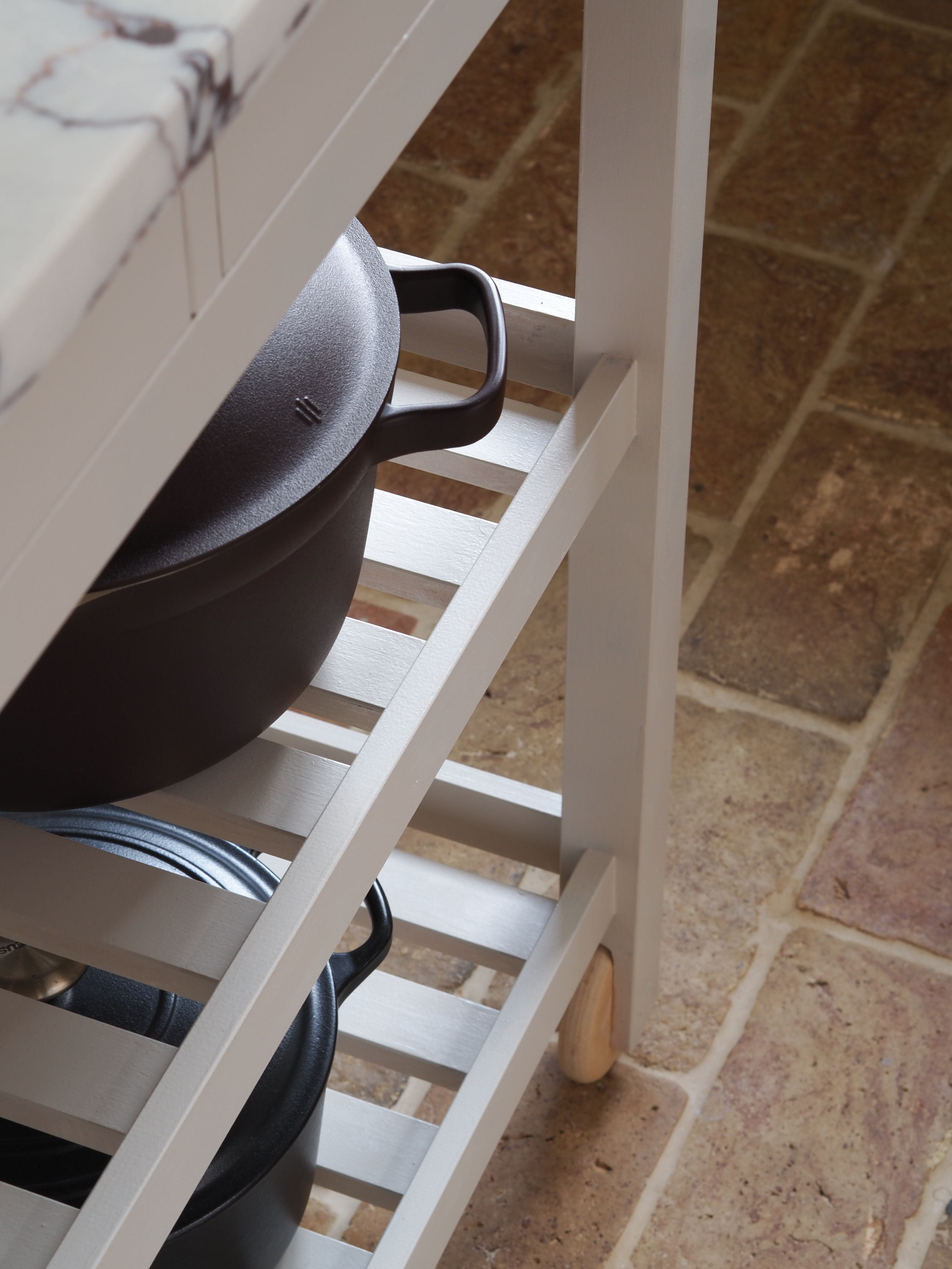 a close up of a neutral kitchen island with a marble top